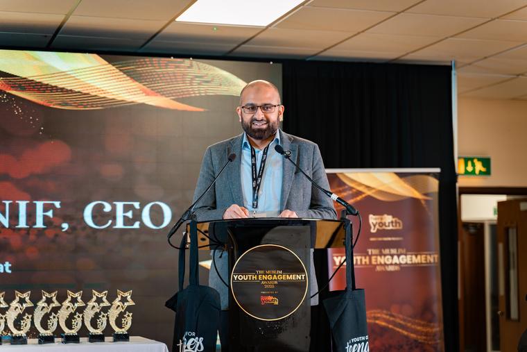 A speaker addressing the room from the stage.