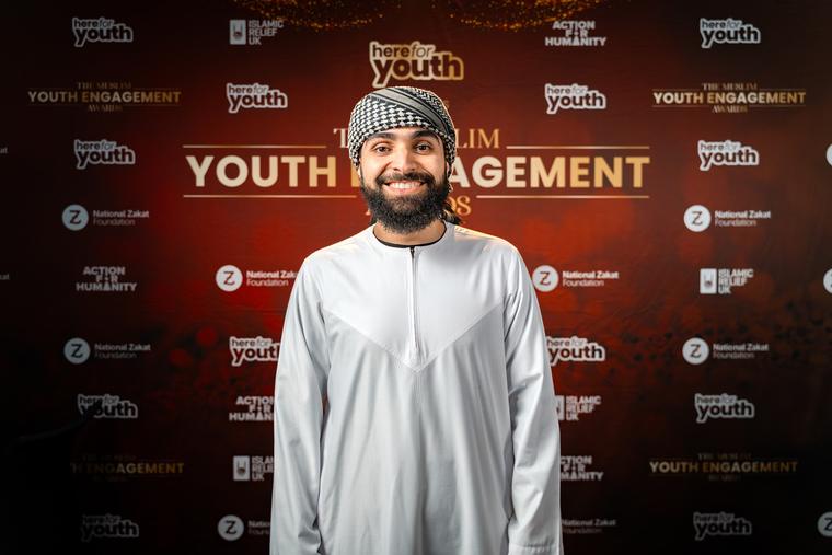 A guest photographed in front of the awards backdrop.