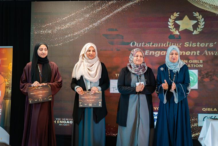 Four award recipients on stage holding certificates.